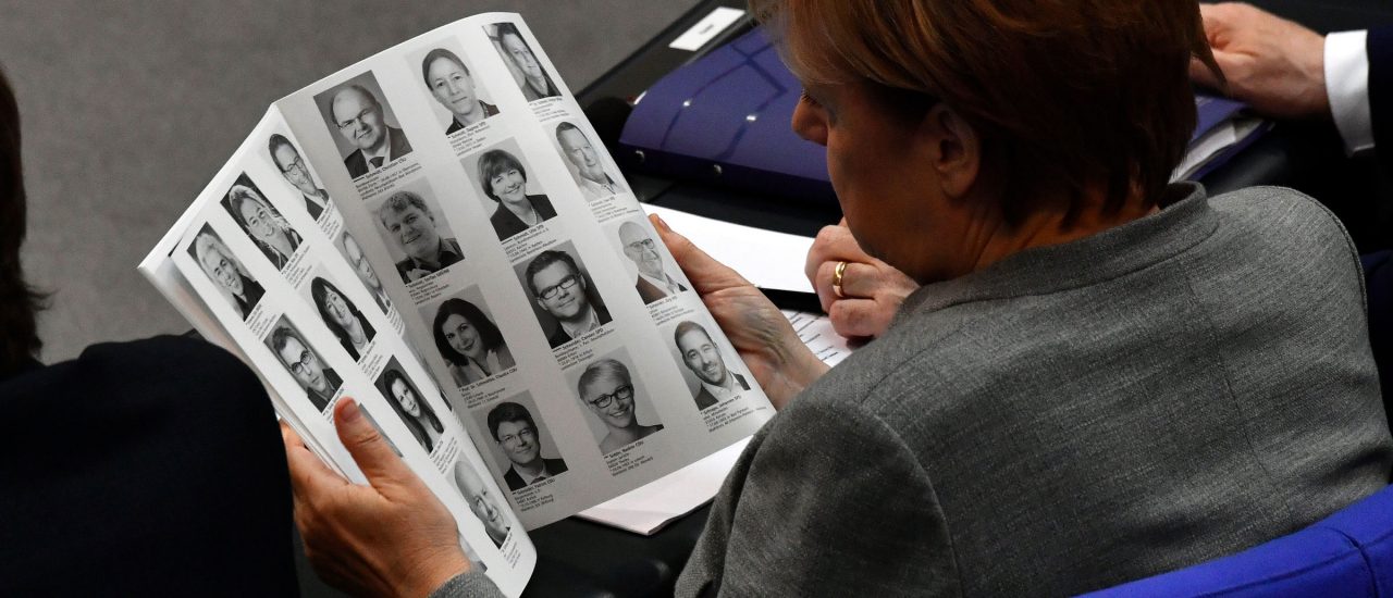 Angela Merkel beim Blick in das Abgeordneten-Verzeichnis des neuen Bundestags. Foto: John MacDougall |AFP