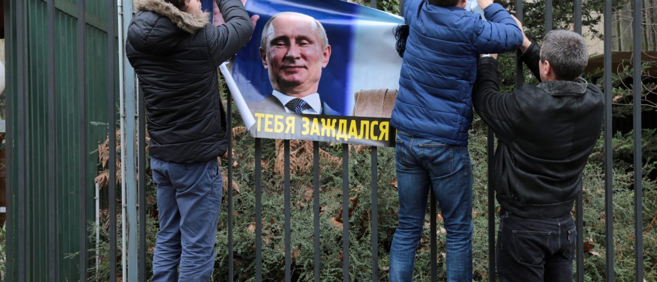 Putin-Gegner hängen ein Protest-Plakat an einen Zaun der russischen Botschaft in Paris. Foto: Zakaria Abdelkafi | AFP