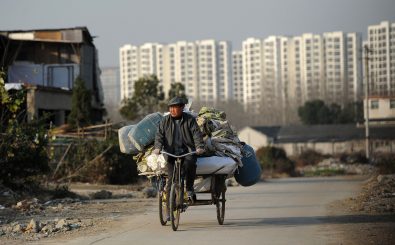 Ein Abfallsammler fährt Fahrrad. Hinter ihm die Hochhäuser der chinesischen Stadt Hefei. Foto: STR | AFP
