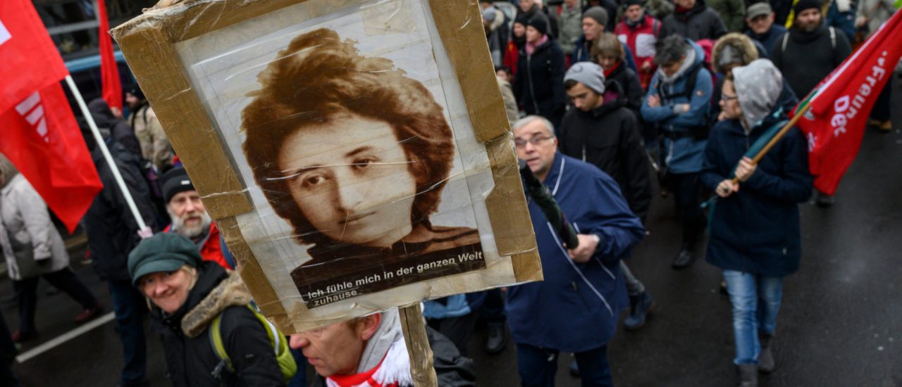 Bei einem Gedenkmarsch zeigt ein Demonstrant ein Plakat mit Rosa Luxemburg.