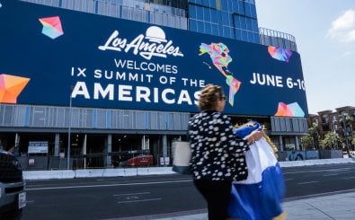 LOS ANGELES, CALIFORNIA – JUNE 06: A woman carries a Nicaraguan flag as she walks by a display advertising the Ninth Summit of the Americas on June 06, 2022 in Los Angeles, California. Leaders from North, Central and South America will travel to Los Angeles for the summit to discuss issues such as trade and migration. The United States is hosting the summit for the first time since 1994, when it took place in Miami.   Anna Moneymaker/Getty Images/AFP (Photo by Anna Moneymaker / GETTY IMAGES NORTH AMERICA / Getty Images via AFP)