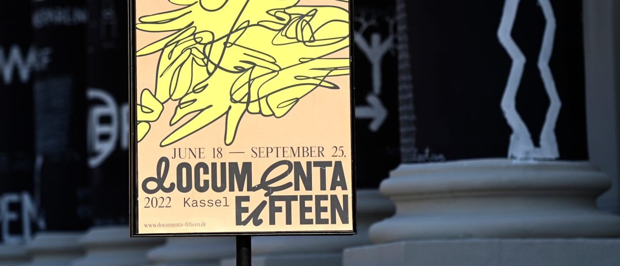A photo shows a placard of the documenta fifteen contemporary art exhibition in front of black painted columns with drawings by Romanian artist Dan Perjovschi at the Fridericianum Museum in Kassel, central Germany, on June 16, 2022. – documenta 15 takes place at 32 exhibition and event venues in Kassel from June 18 to September 25, 2022 and is curated by Indonesian artists collective ruangrupa. (Photo by Ina FASSBENDER / AFP)