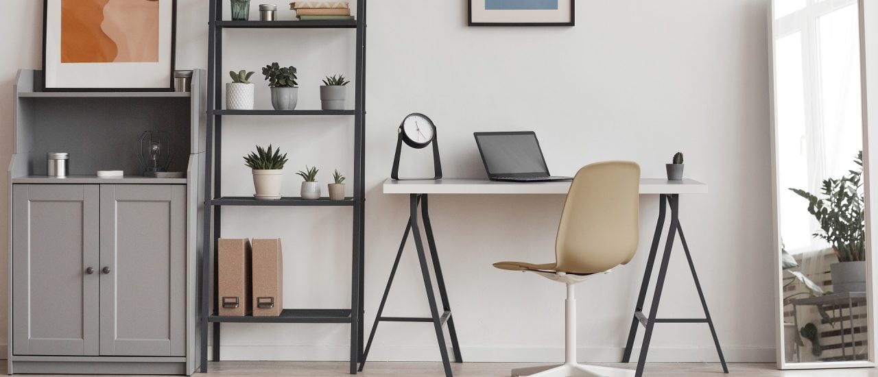 Hintergrund der minimalen Heimbüros in modernen Apartments mit Pflanzen und abstrakter Kunst, Kopienraum. Foto: SeventyFour / Shutterstock