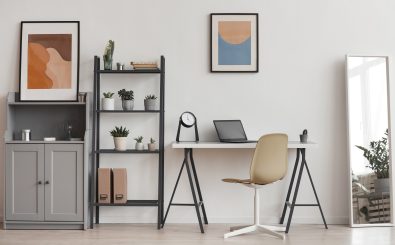Hintergrund der minimalen Heimbüros in modernen Apartments mit Pflanzen und abstrakter Kunst, Kopienraum. Foto: SeventyFour / Shutterstock