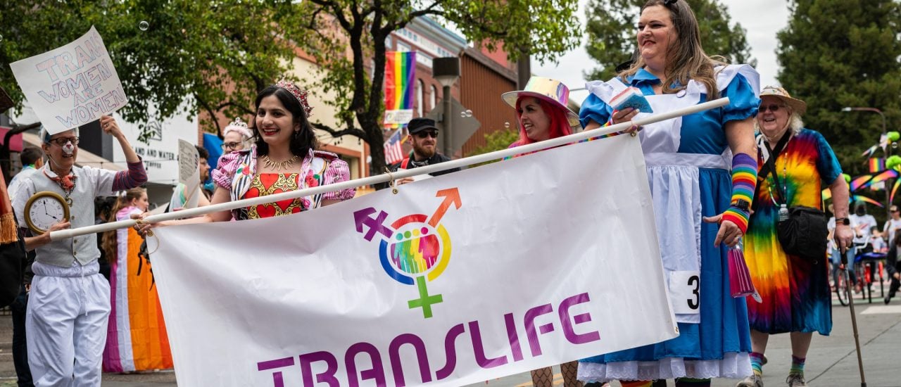 translife-flagge an einer Demo und Menschen in Regenbogenfarbenener Kleidung 