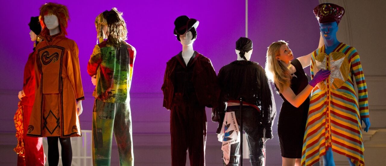 Kate Bethune, assistant curator for textiles and fashions, poses with a piece from the „Paki from Outer Space“ collection by Leigh Bowery (R) at the „Club to Catwalk: London Fashion in the 1980s“ exhibition at the V&A museum in west London on July 8, 2013. Running from the 10th July to 16th February 2014, the exhibition charts the rise of British fashion designers through the 80s club scene and into the newly-created London Fashion Week. AFP PHOTO/LEON NEAL (Photo by LEON NEAL / AFP)