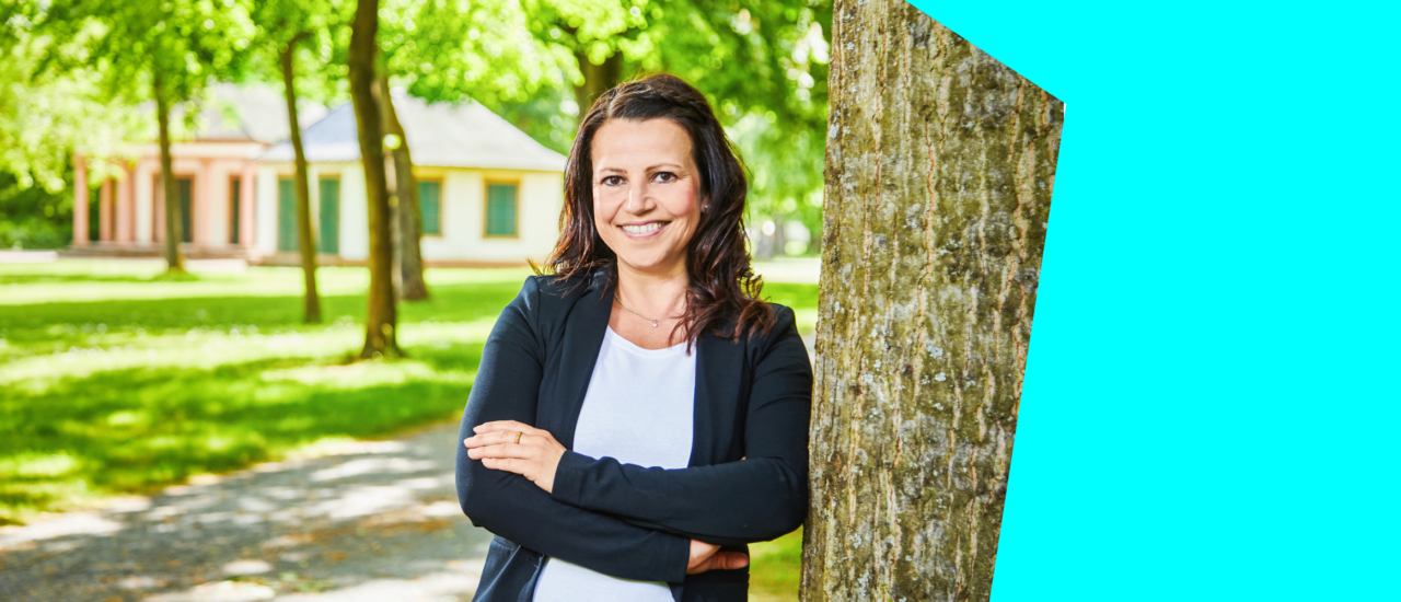 Die Stadtbaumexpertin Daniela Antoni lehnt lächelnd an einem Baum