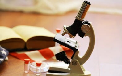 Ein Mikroskop, ein Buch und Reagenzgläser: Symbolbild für Wissenschaftsfreiheit Sachsen-Anhalt. Foto: „alexkich“, Shutterstock