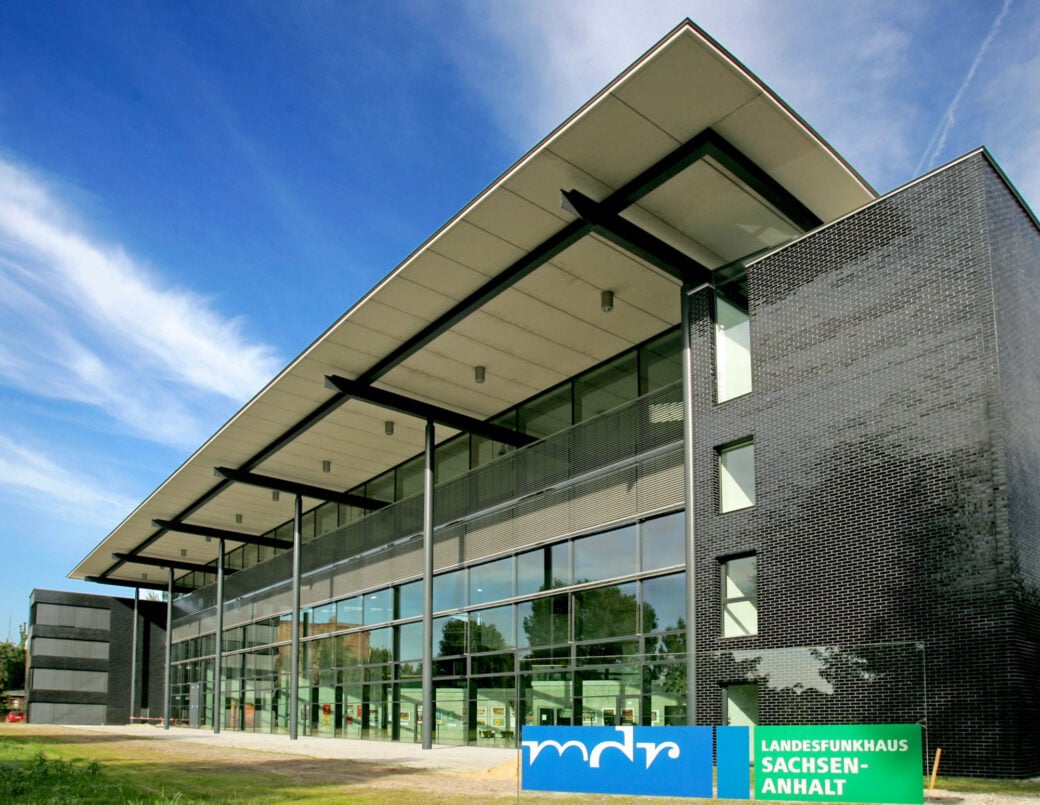 Zu sehen ist das Landesfunkhaus Magdeburg des MDR. Vor dem Gebäude steht ein Schild mit der Aufschrift: MDR Landesfunkhaus Sachsen-Anhalt. Das Haus selbst hat eine große Glasfassade und schwarze Klinker. MDR-Staatsvertrag Kündigung AfD
