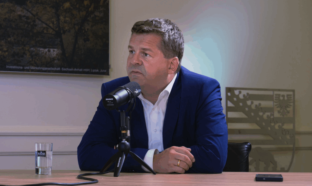 Sven Schulze (CDU), der amtierende Ministerpräsident von Sachsen-Anhalt, sitzt während eines Interviews für den Sachsen-Anhalt-Podcast DAZWISCHEN in Anzug und Krawatte an einem Tisch in der Staatskanzlei vor einem detektor-fm-Mikrofon.
